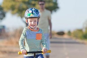 smiling happy little boy at the balance bike and his young father in the background